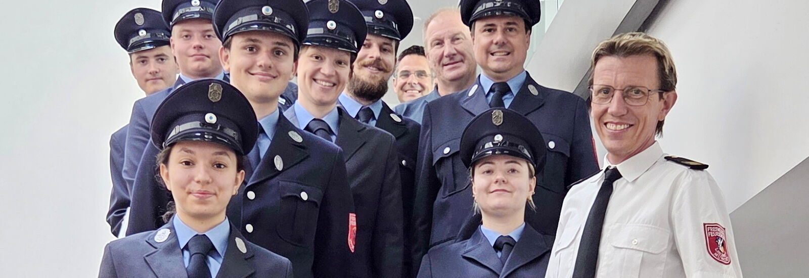 Feuerwehrkamerad:innen und -kameraden nach bestandener Prüfung auf der Treppe im Feuerwehrhaus